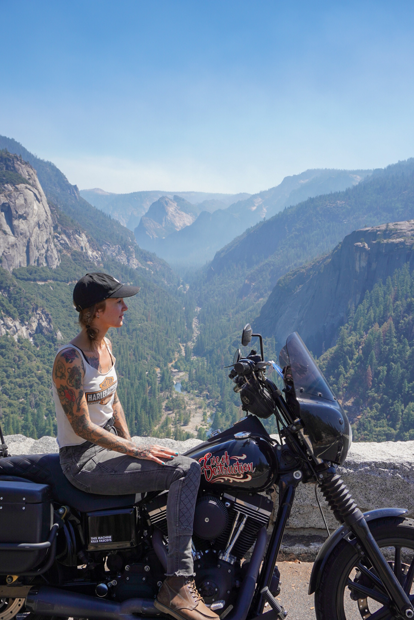 Women sitting on motorcycle overlooking a deep, scenic valley